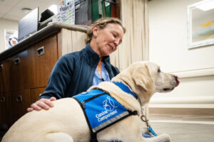 Peppi, a yellow Lab and official “Canine Companion,” sits on the lap of OB - GYN Kristina Fraser in November at the HCA HealthONE Rose medical center in Denver. (Hart Van Denburg/CPR News)